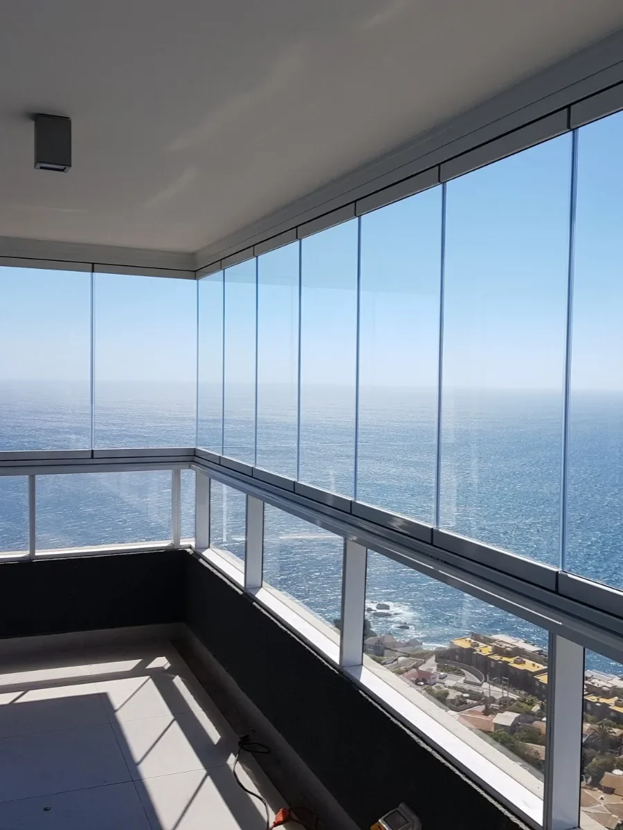Balcón de departamento cerrado con vidrio plegable y vista al mar
